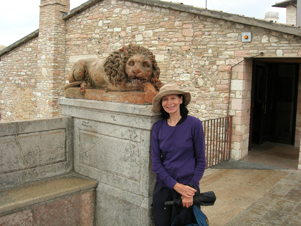 Wendy MacIntyre posed with stone lion sculpture in Assisi